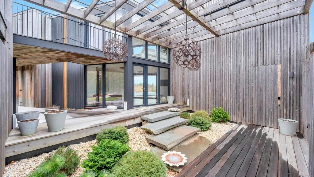 Un patio exterior moderno con tarima de madera, escalones y vegetación.