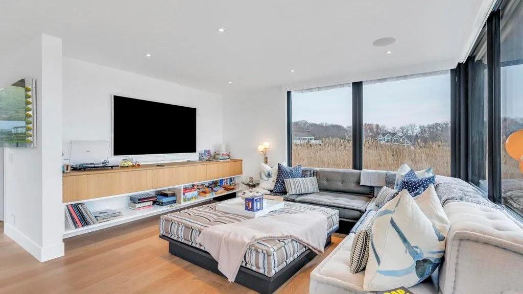 Una sala luminosa con una zona de asientos y grandes ventanales.
