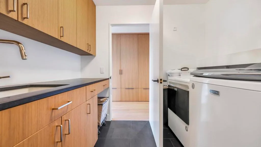 Una cocina compacta con gabinetes de madera, una encimera oscura y una estufa blanca.