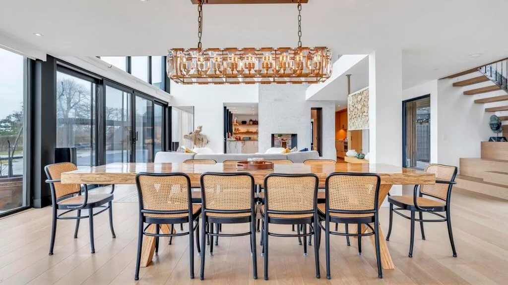 Un comedor luminoso tiene una larga mesa de madera bajo una lámpara colgante.