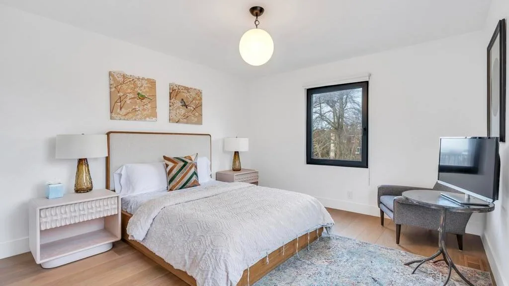 Un dormitorio con una cama, mesitas de noche y un televisor.