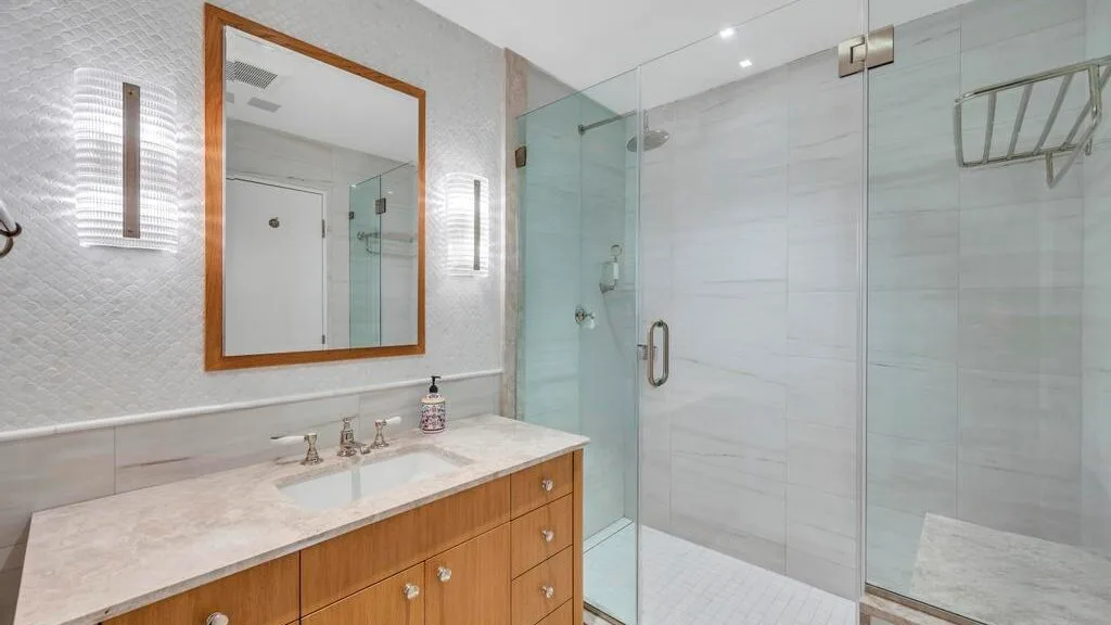 Un baño luminoso con lavabo y ducha con mampara de vidrio.