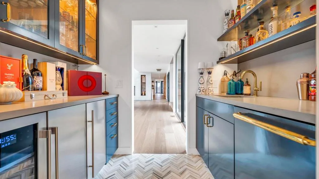 Una cocina moderna con gabinetes azules y un pasillo visible al fondo.