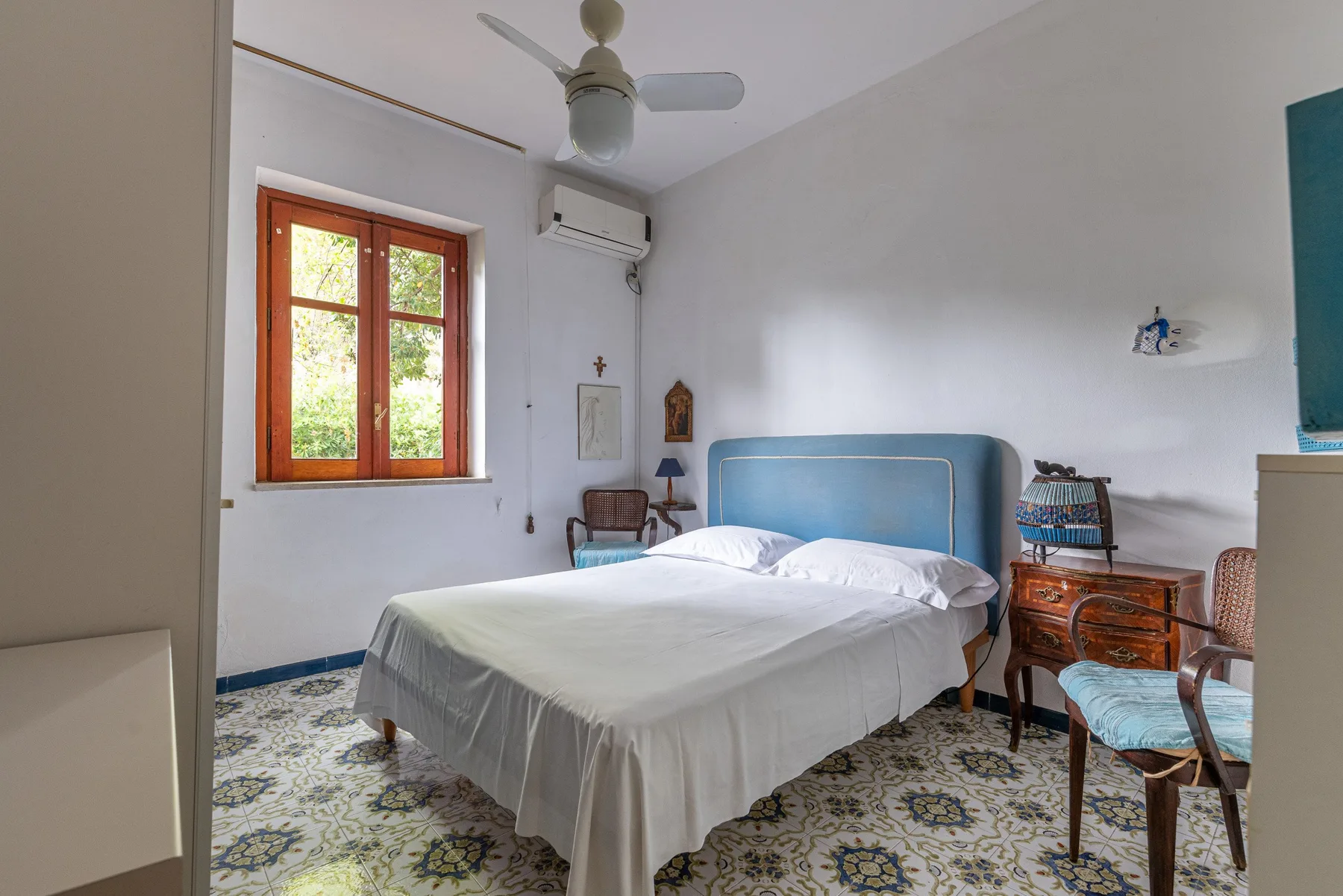A bedroom with a bed, a window, and patterned floor tiles.