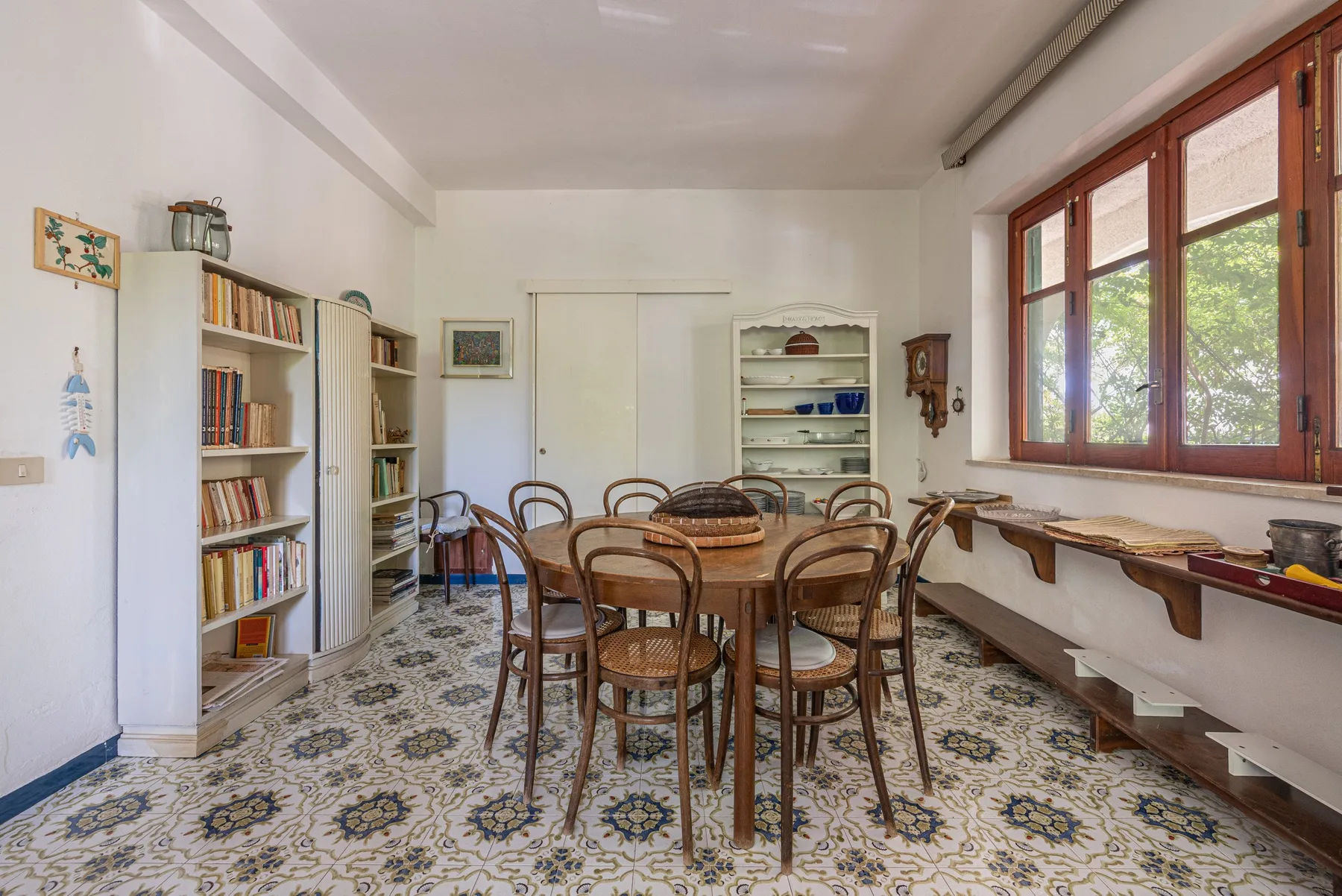 A dining area with a round table and chairs beside large windows.