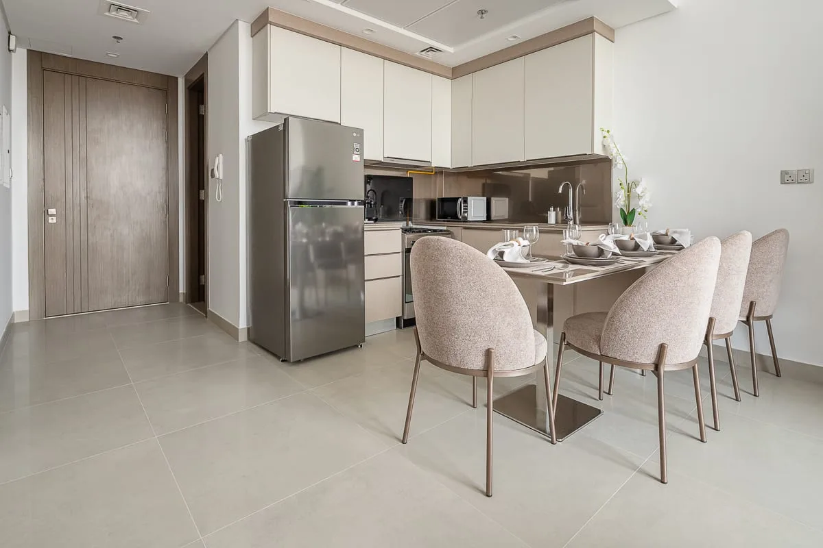 A dining area with a set table and upholstered seating beside a kitchen.