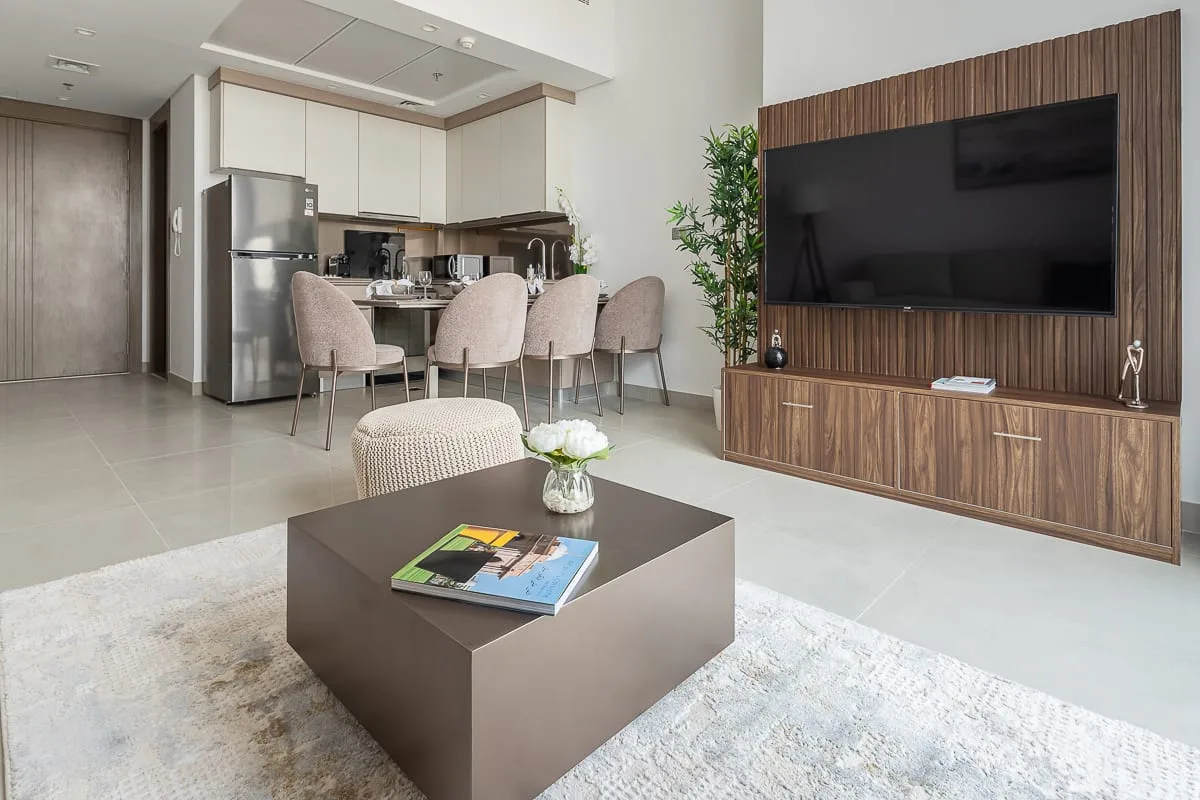 A modern living room with a television wall and an adjoining kitchen.