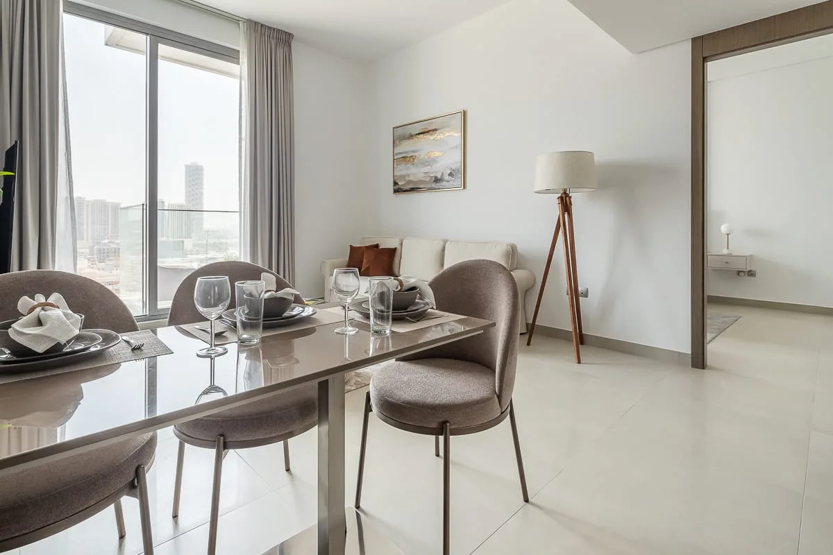 A dining area with a set table beside a large window and a seating area.