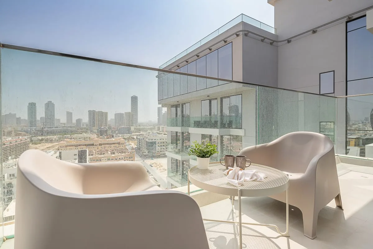 A balcony seating area overlooks the city, with a small table between two seats.