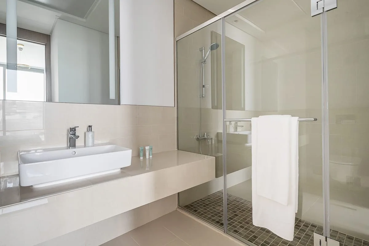 A modern bathroom with a wide sink counter and glass shower.