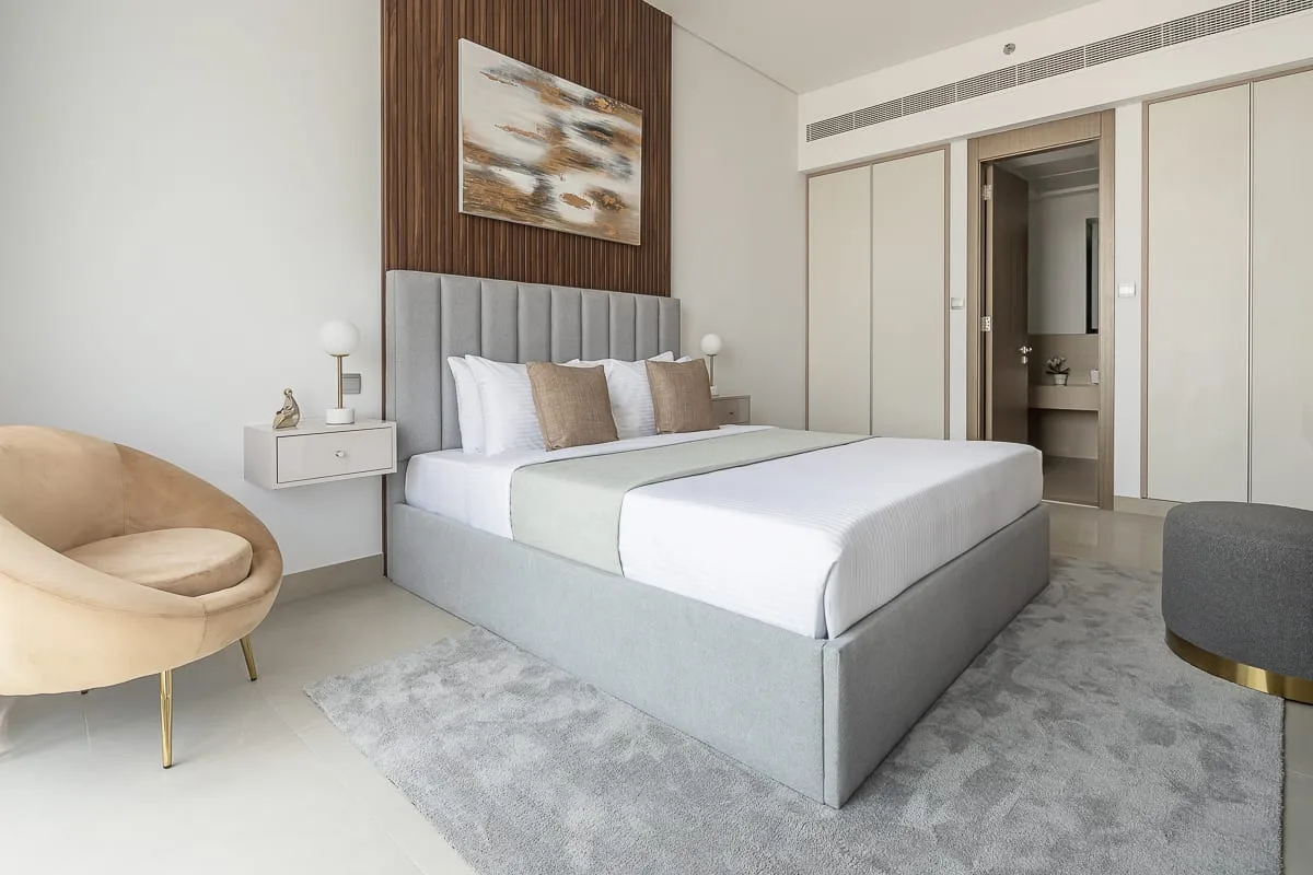 A bedroom with a large bed, bedside table, and an upholstered chair.