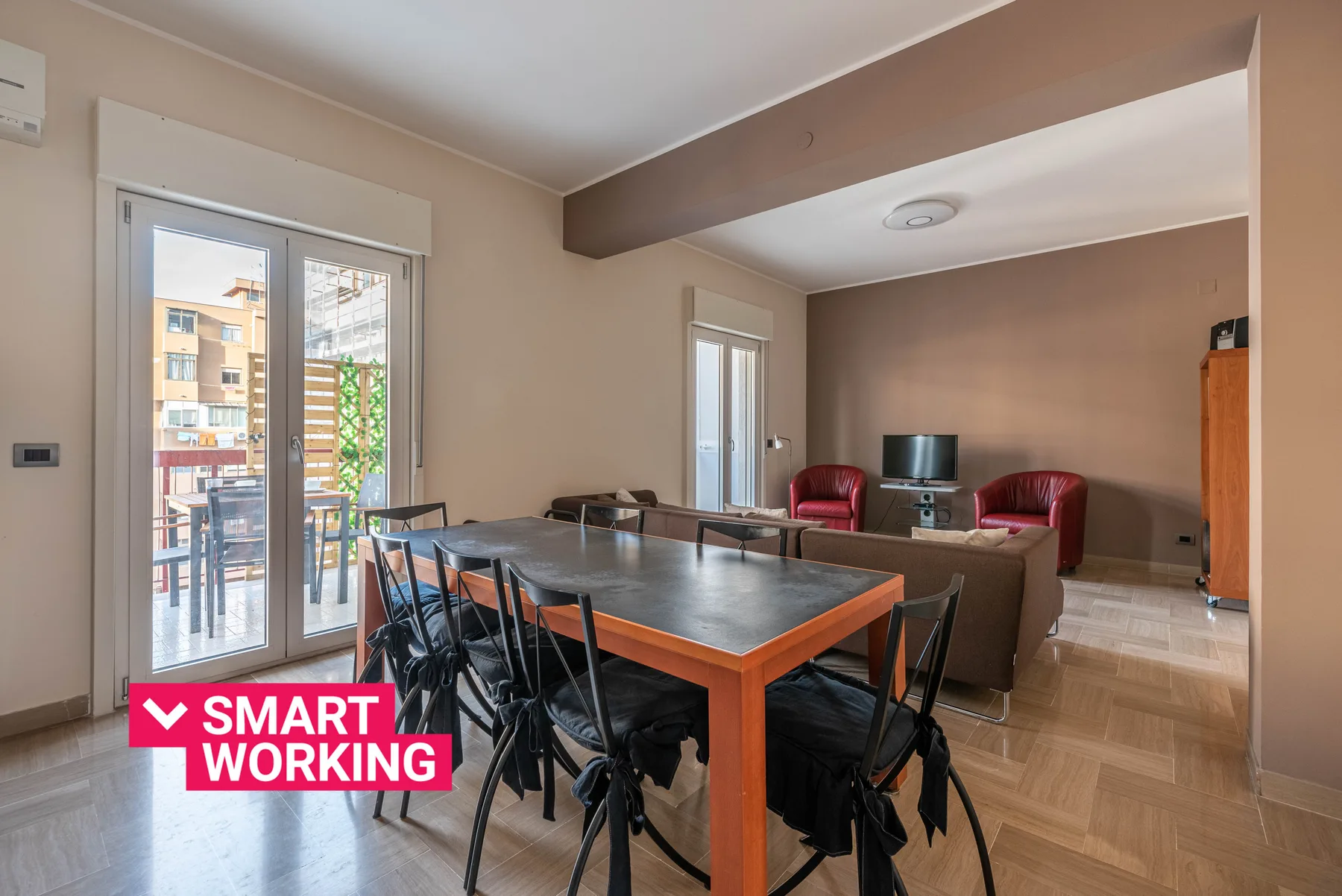 A dining area with a long table and chairs opens onto a living room.