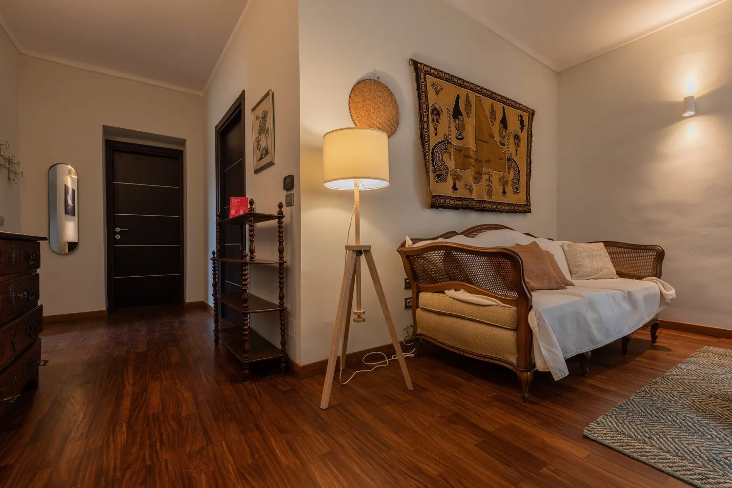 Dormitorio con una cama, una lámpara de pie y decoración estampada en la pared.