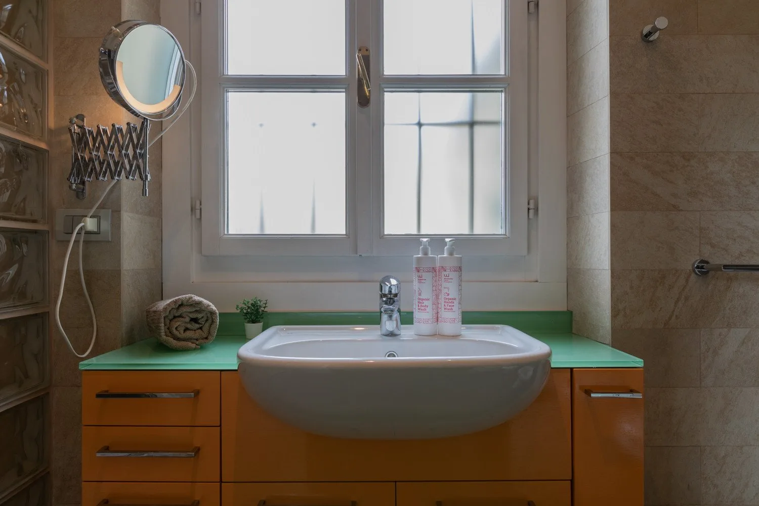 Un lavabo de baño está situado debajo de una ventana grande.