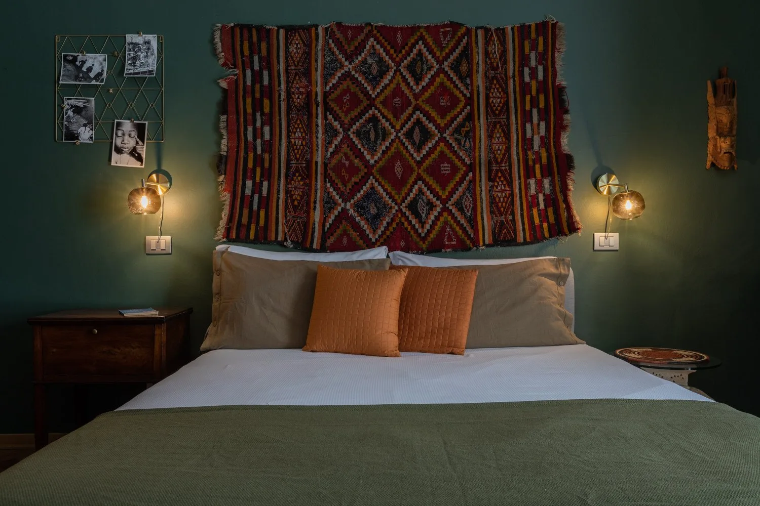 Un dormitorio con una cama bien tendida y un textil estampado colgado en la pared.