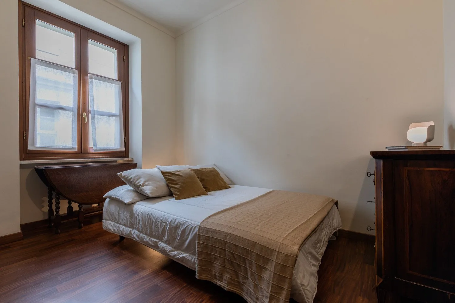 Un dormitorio con una cama junto a una ventana alta.