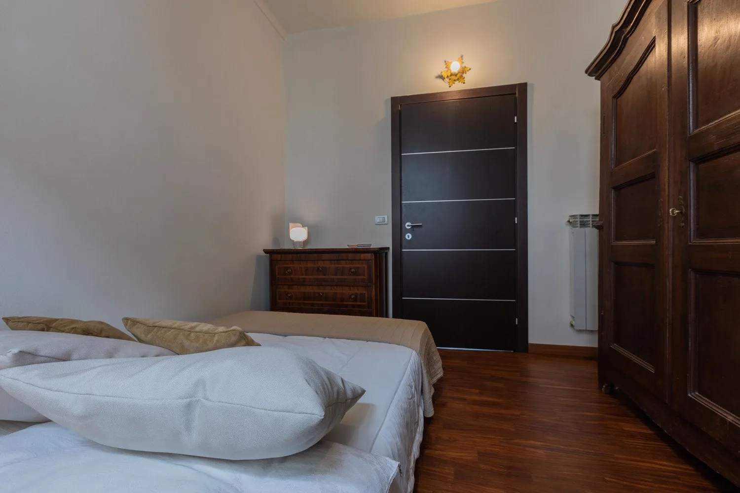 Un dormitorio con una cama, una puerta oscura y un armario de madera.