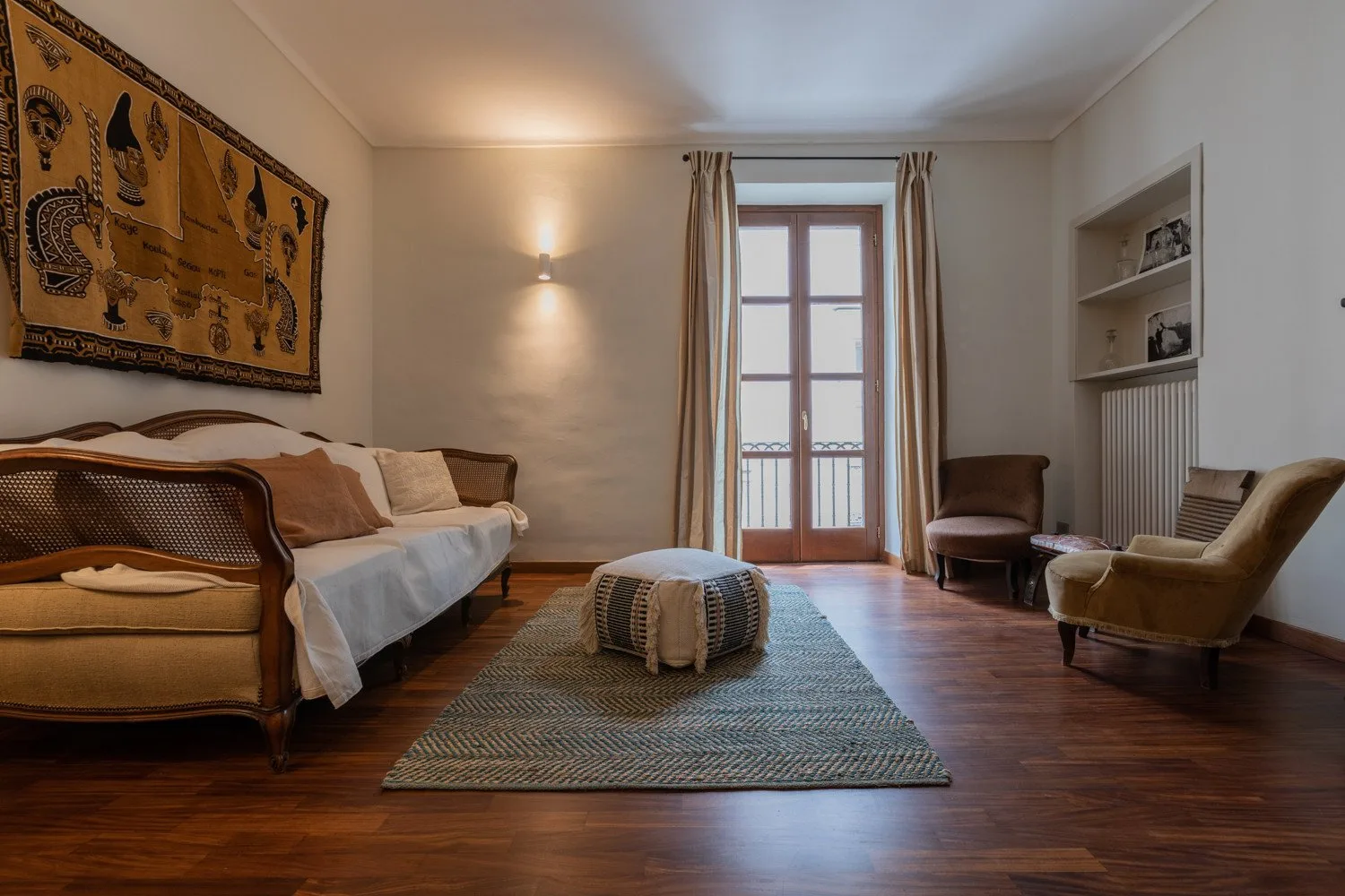 Una sala de estar con asientos, una alfombra central y puertas con paneles de vidrio.