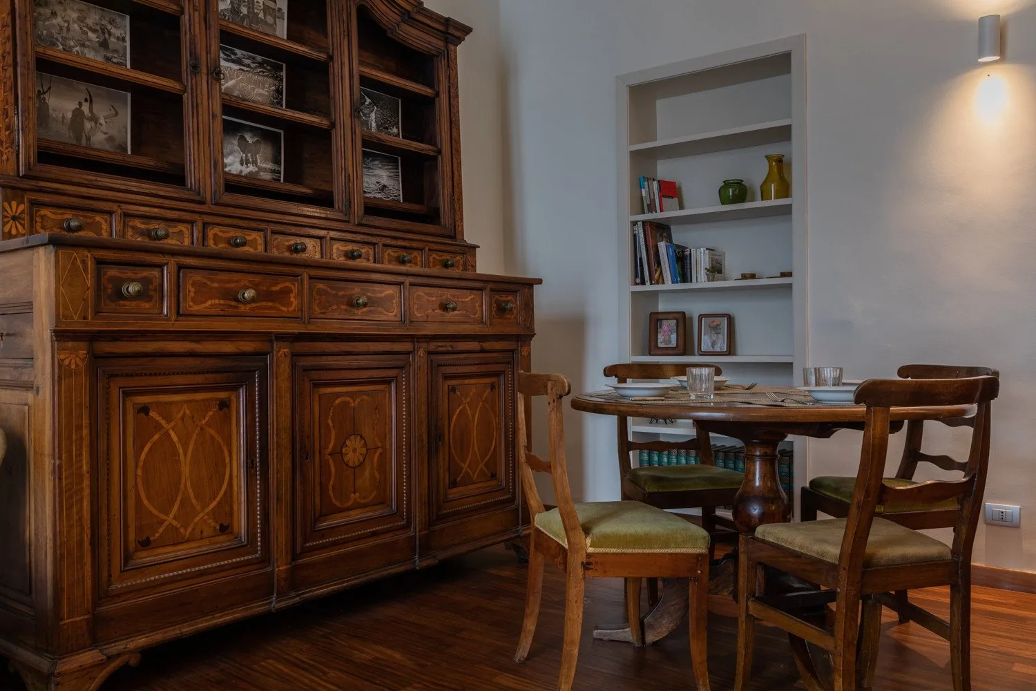 Comedor con una mesa de madera, sillas y un gran mueble vitrina.