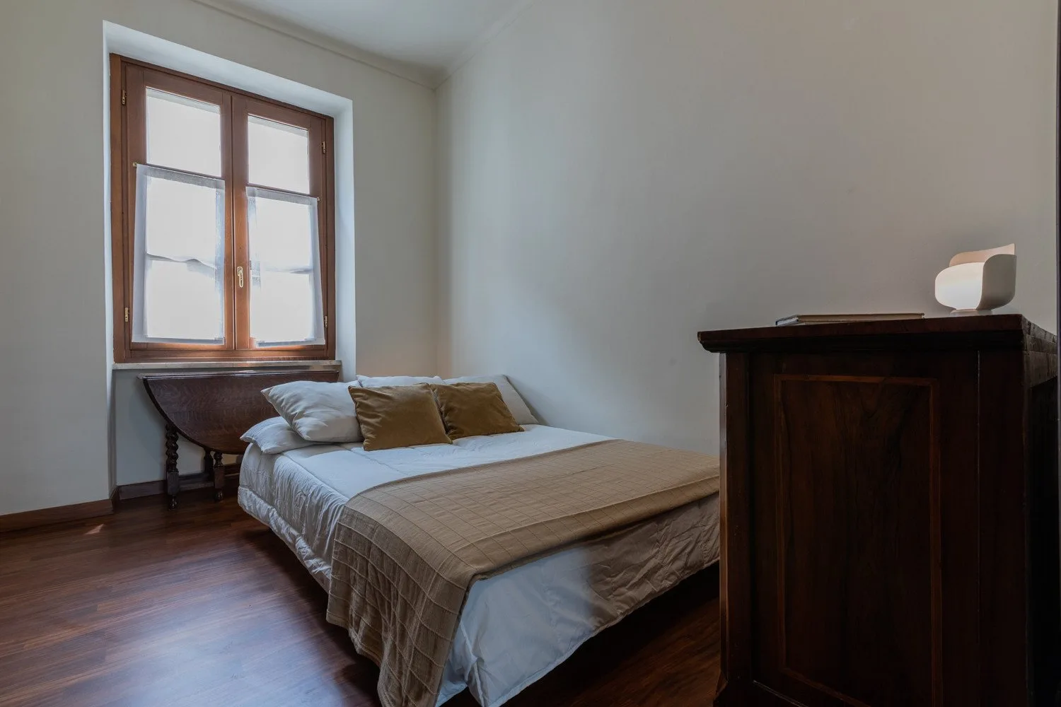 Un dormitorio con una cama bajo una ventana con marco de madera.