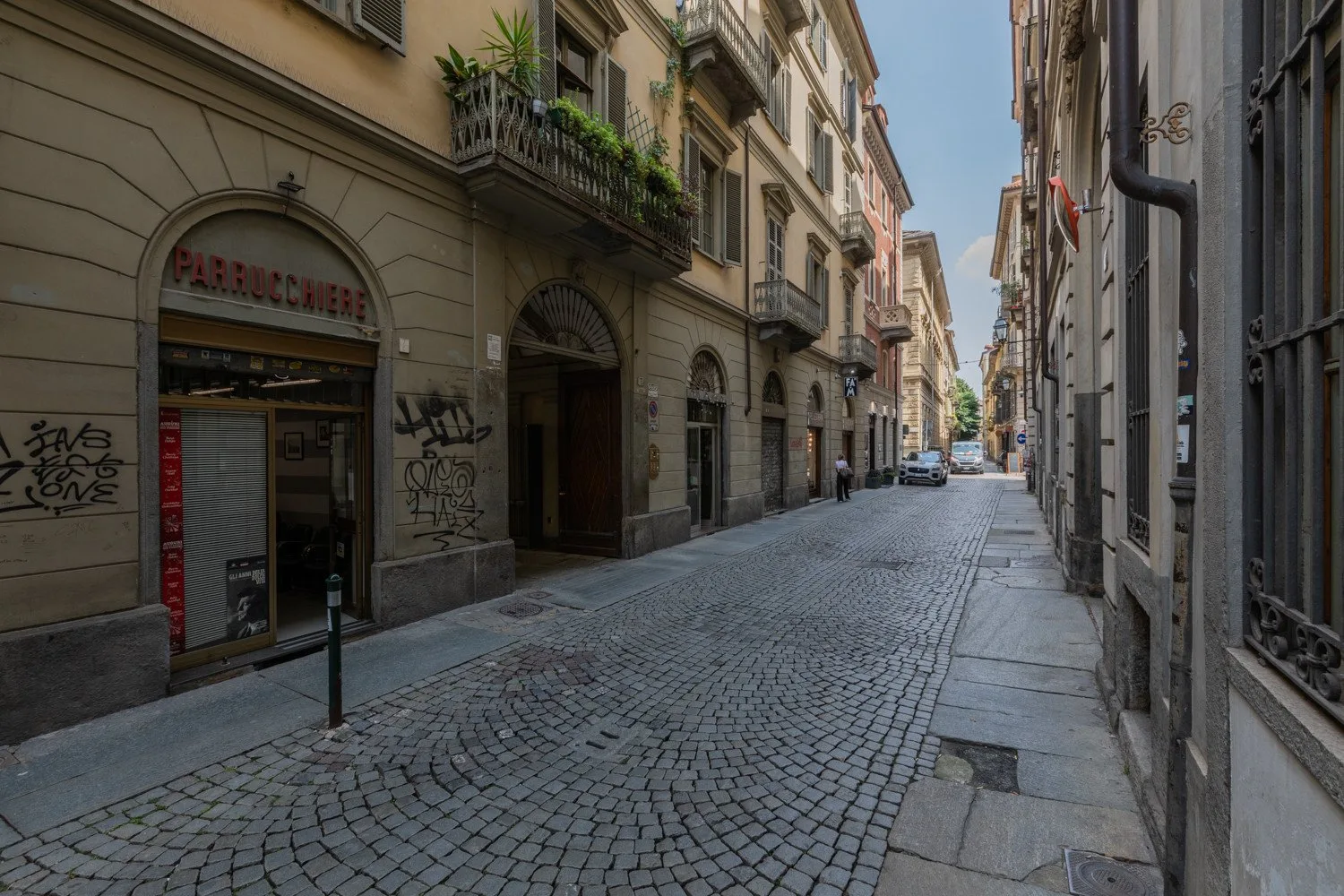 Una calle estrecha empedrada pasa entre edificios cercanos con locales comerciales.