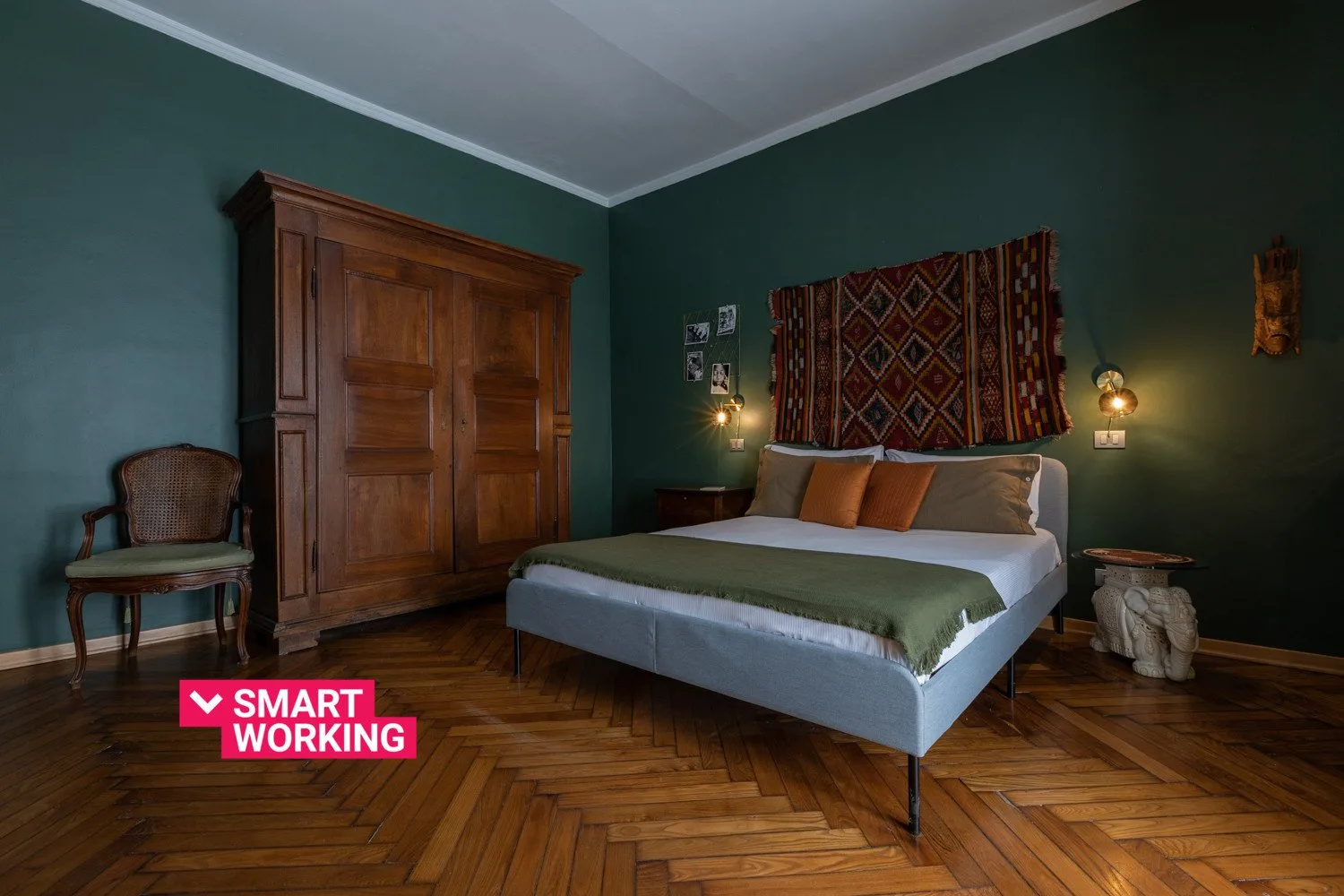 Un dormitorio con una cama, un armario de madera y un tapiz estampado.