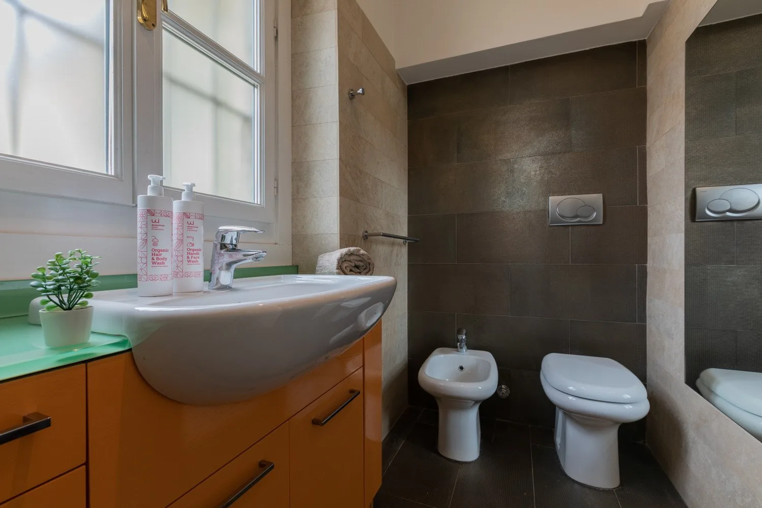 Un baño con lavabo, bidé e inodoro junto a una ventana.
