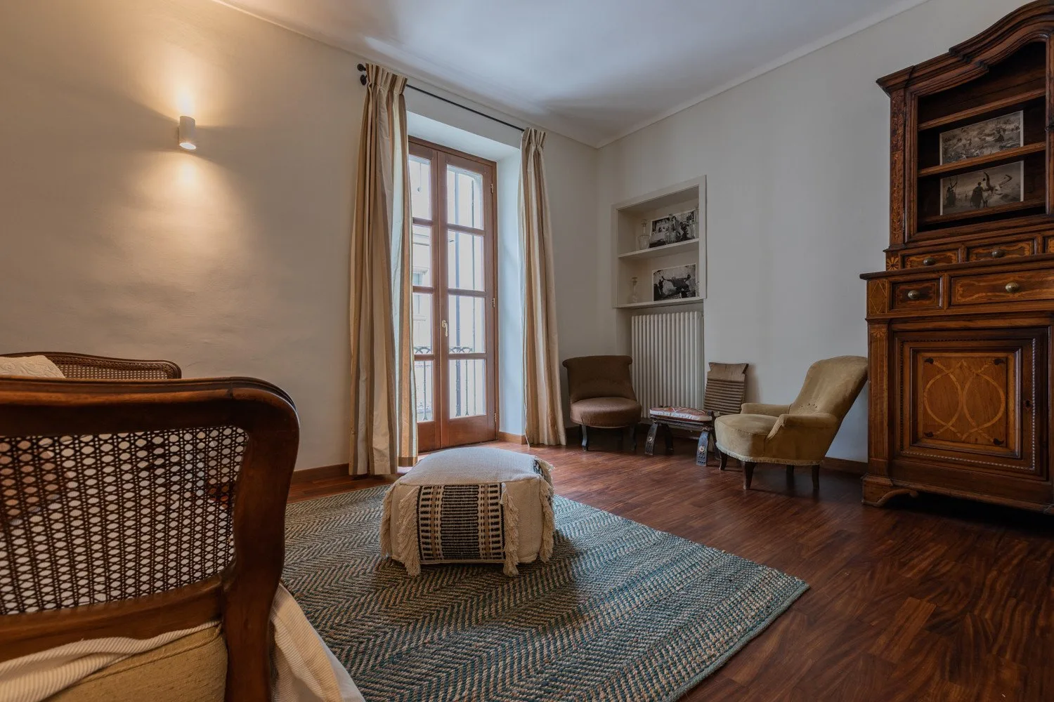 Una sala de estar con una alfombra estampada y puertas acristaladas altas.