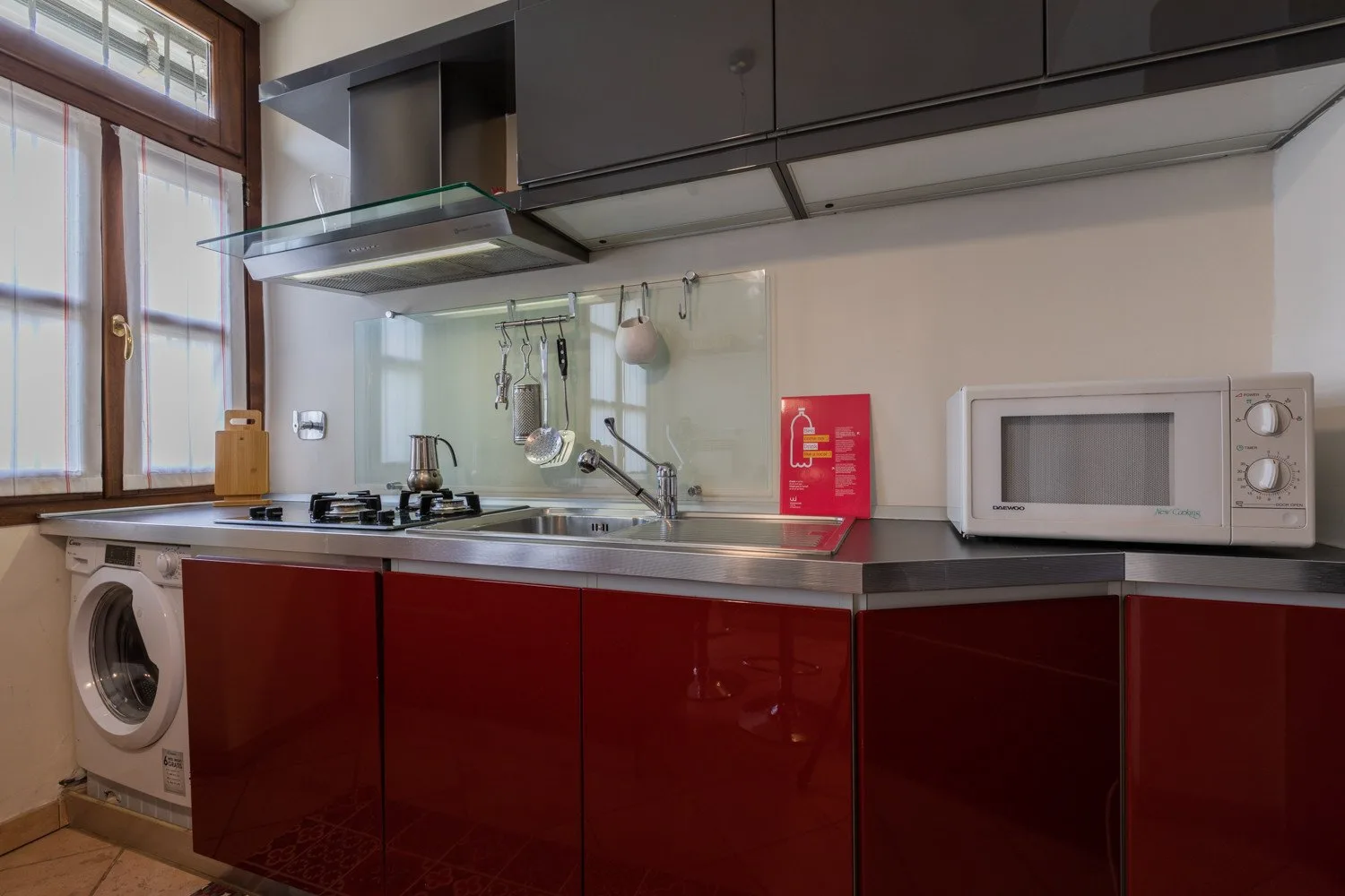 Una cocina con gabinetes rojo oscuro, un fregadero y un microondas.