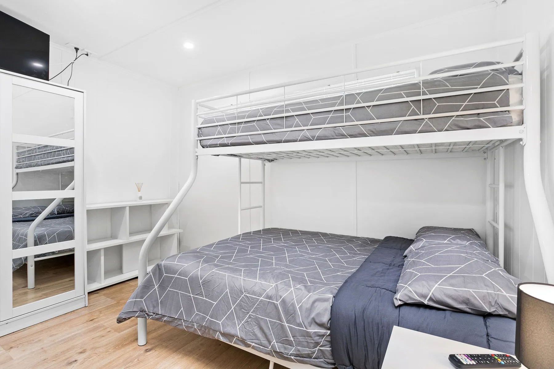 Un dormitorio con una cama doble debajo de una litera con estructura metálica.