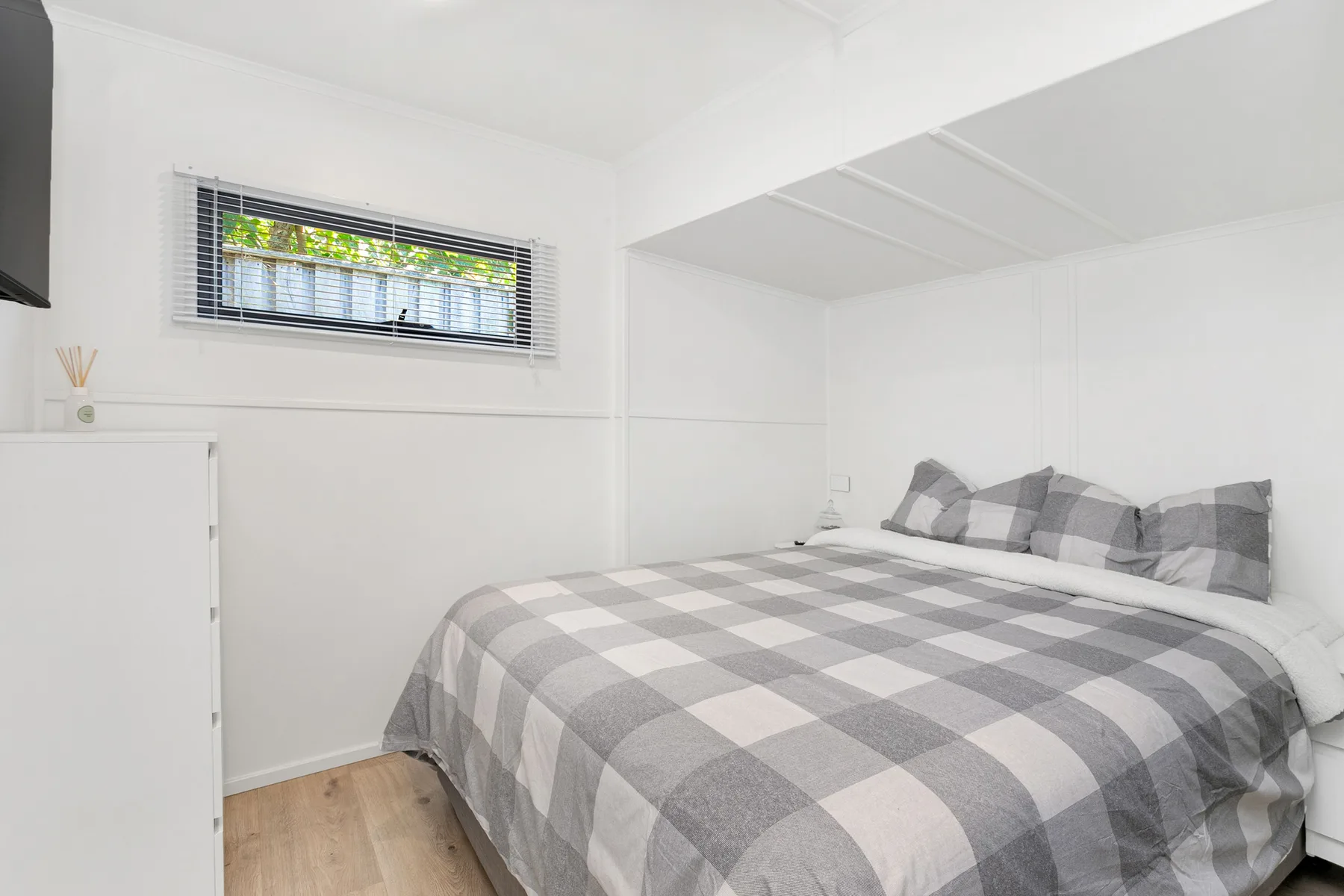 Un dormitorio con una cama cubierta con una manta gris a cuadros.