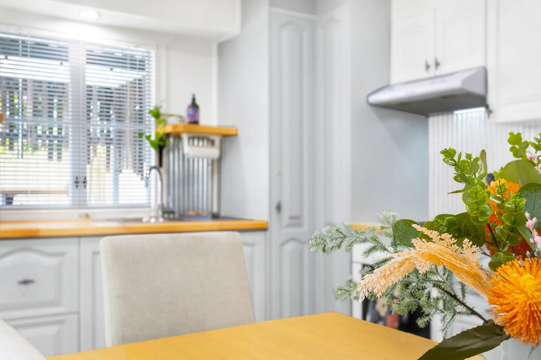 Una cocina luminosa con gabinetes blancos, una encimera y una mesa.