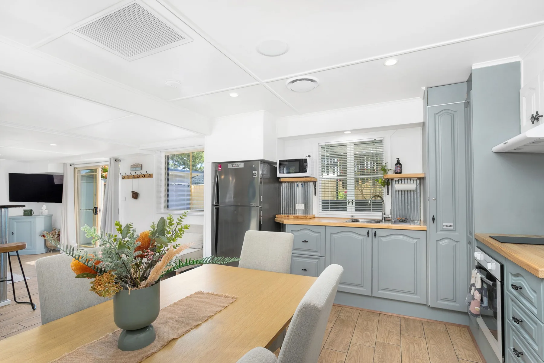 Cocina y comedor con gabinetes grises y una mesa de madera.