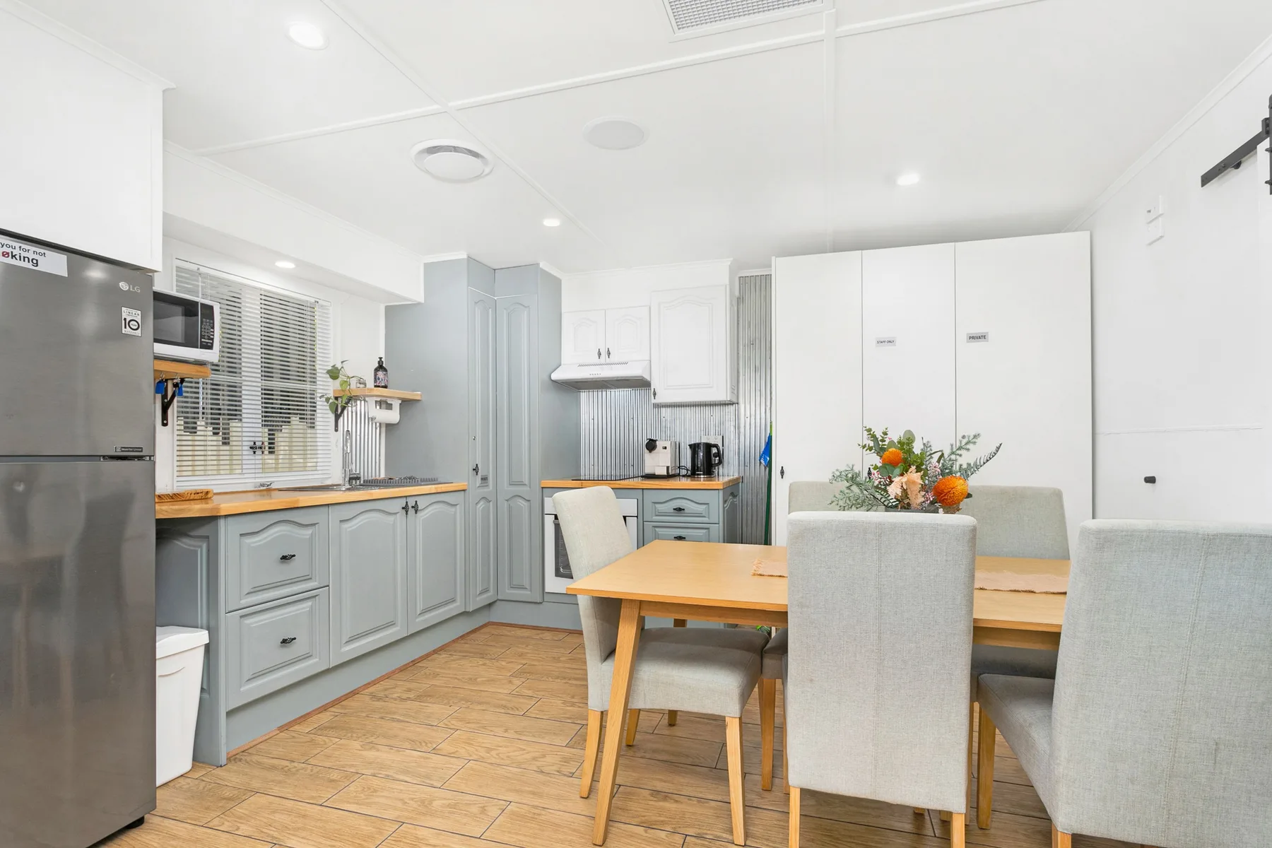 Una cocina y comedor luminosos con gabinetes claros y una mesa de madera.