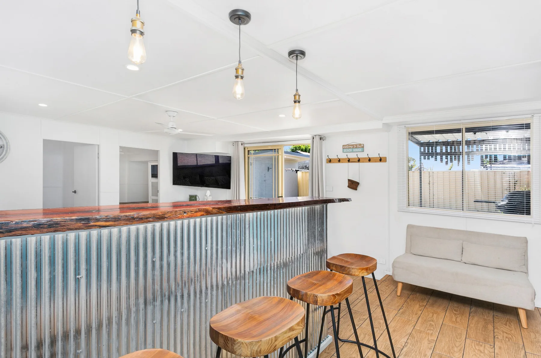 Una luminosa zona de bar tiene una barra acanalada, taburetes de madera y un pequeño espacio de estar.