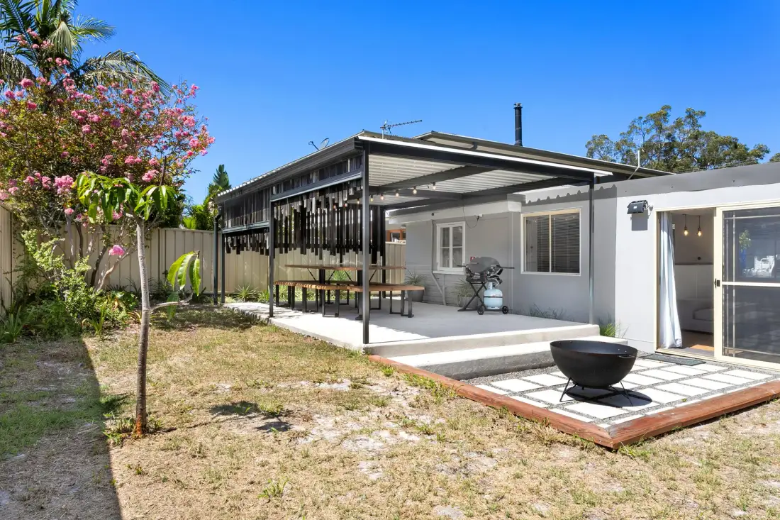Un patio de una casa con una zona de estar cubierta y un pequeño espacio pavimentado.