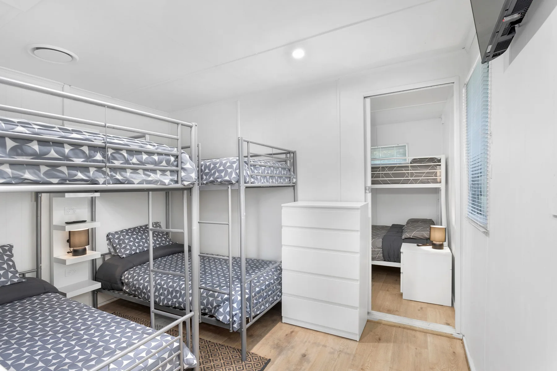 Un dormitorio luminoso con literas y una cómoda blanca.