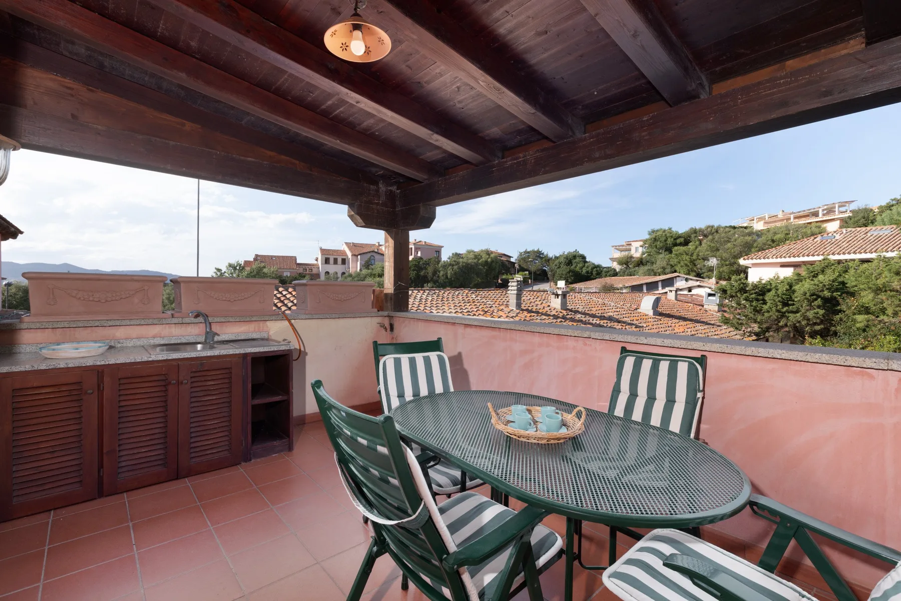 Una terraza cubierta en la azotea, con mesa y asientos, mira hacia los tejados cercanos.