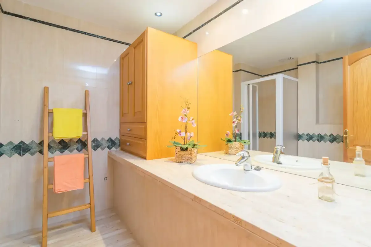 Un baño con lavabo, un espejo grande y un armario de madera en la pared.