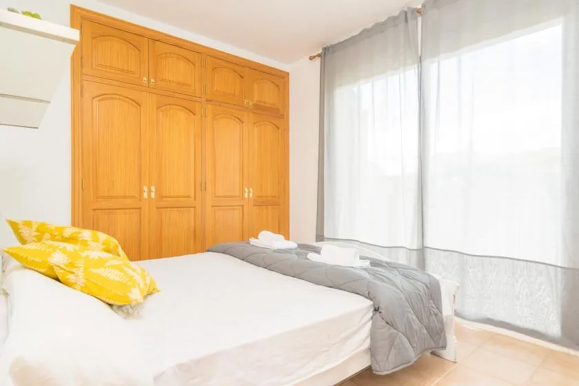 Un dormitorio con una cama, almohadas amarillas y un armario grande.