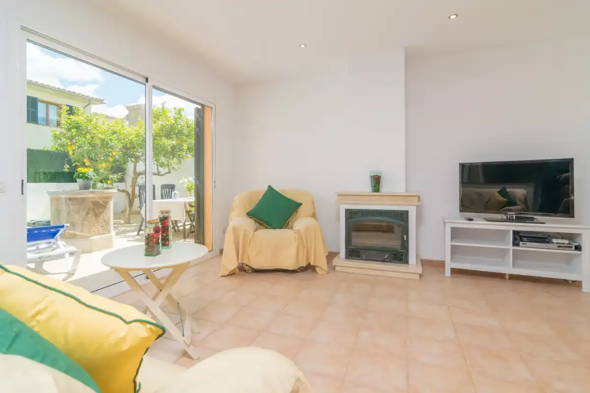 Una sala de estar luminosa con asientos, un televisor y puertas de vidrio que dan a un patio.