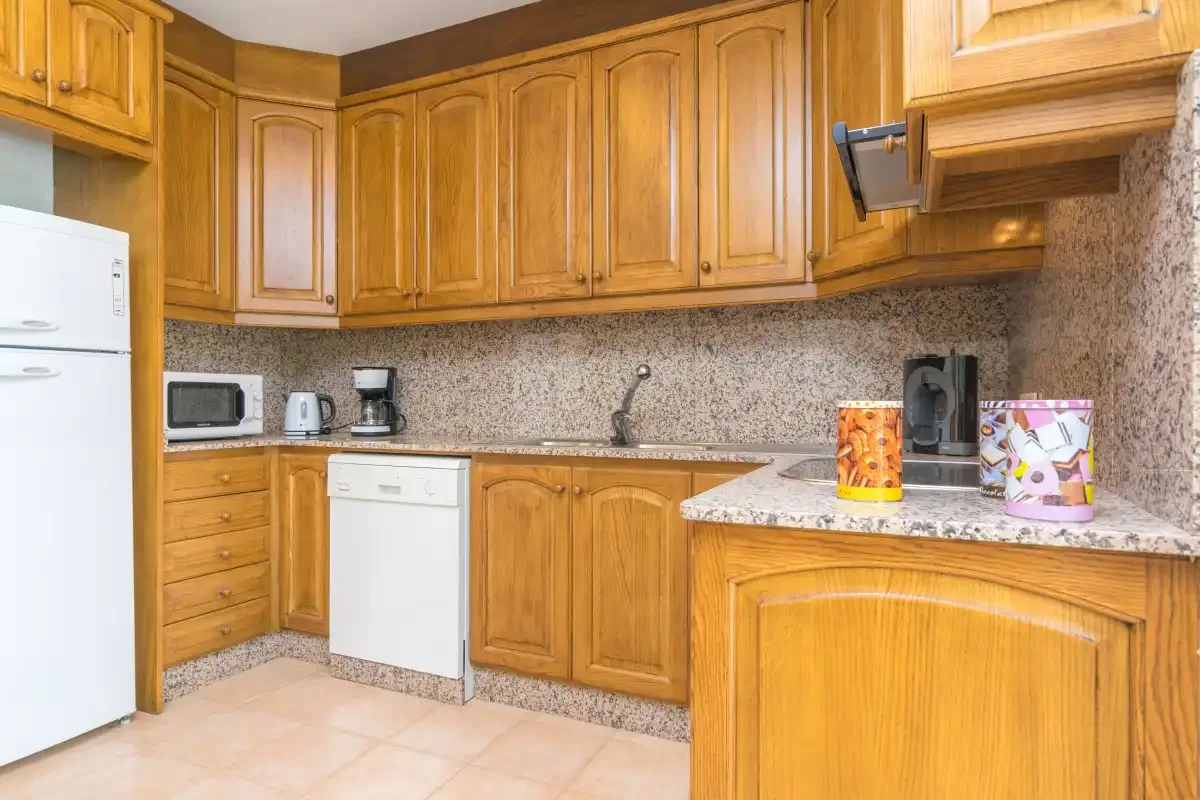 Una cocina con armarios de madera y una encimera con estampado de piedra.