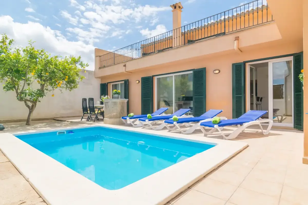 Una piscina y tumbonas están junto a una casa con terraza.