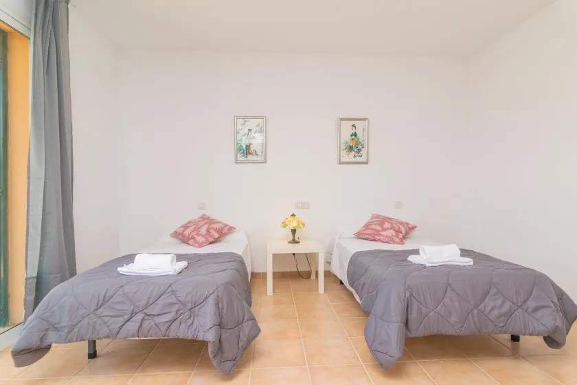 Un dormitorio con dos camas individuales, una mesita y cuadros enmarcados.