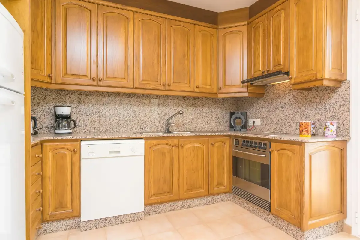 Una cocina con armarios de madera, una encimera y electrodomésticos integrados.