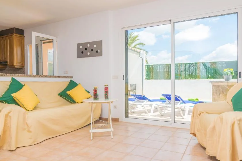 Una sala luminosa con asientos cubiertos junto a una puerta corrediza de vidrio.