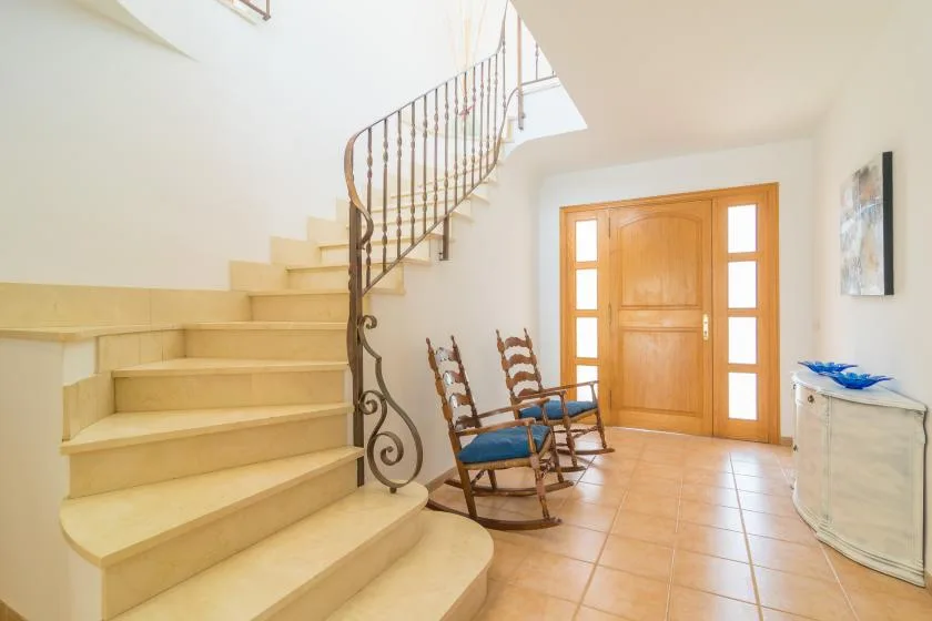 Una entrada luminosa con una escalera curva y puertas dobles de madera.