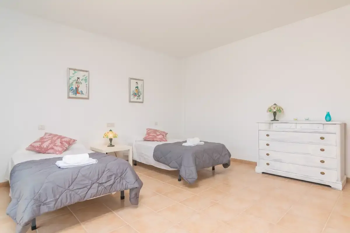 Un dormitorio luminoso con dos camas, una cómoda y cuadros en la pared.