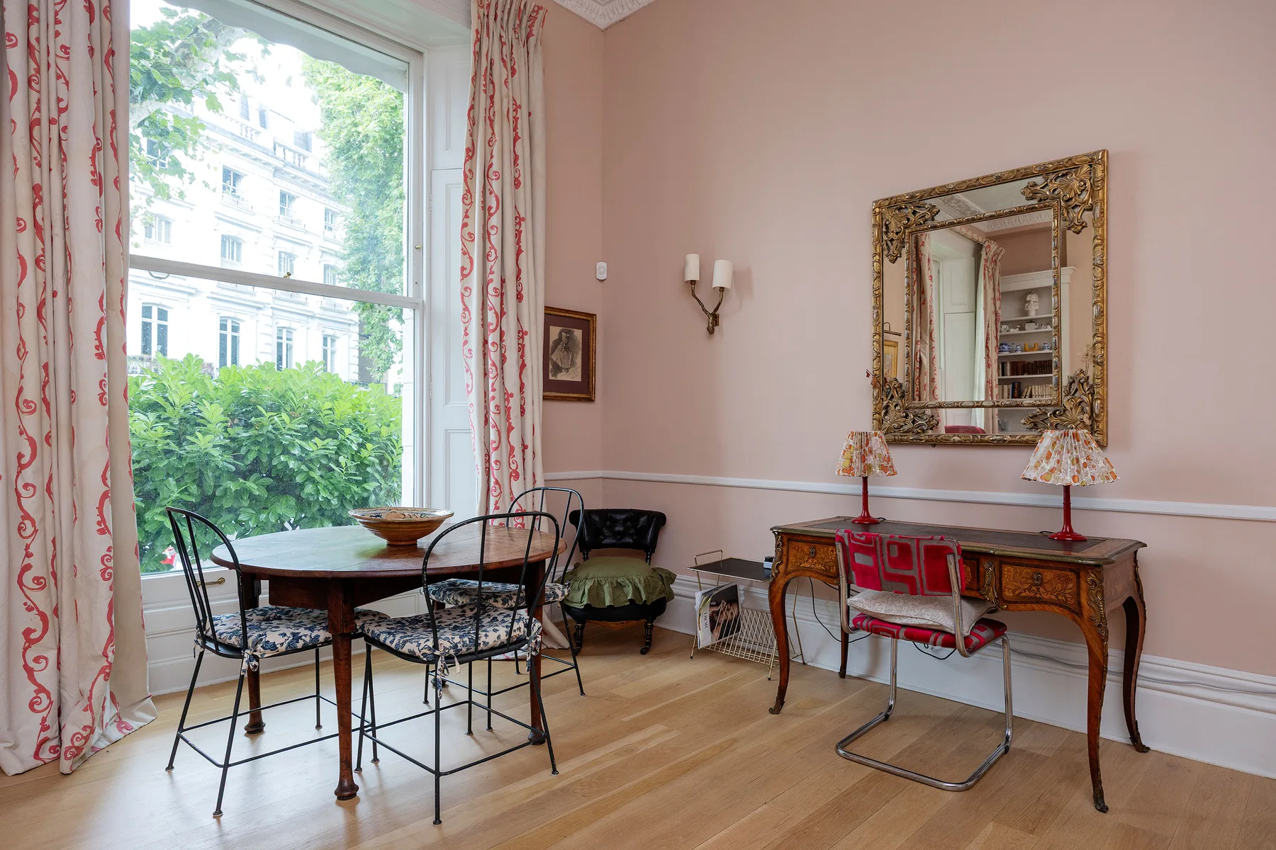 A dining area with a table and chairs beside a large window.
