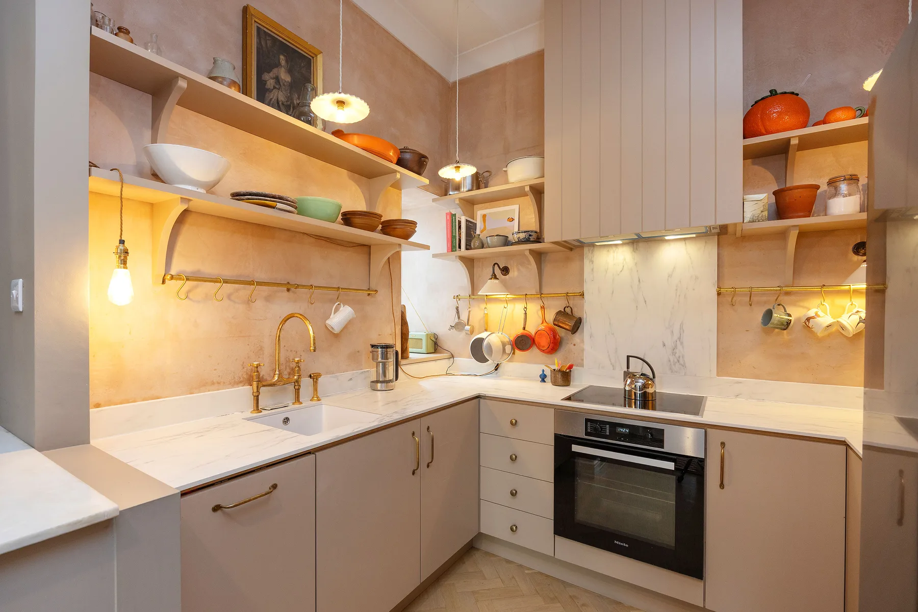 Una cocina compacta con gabinetes claros, estantes abiertos y un horno empotrado.
